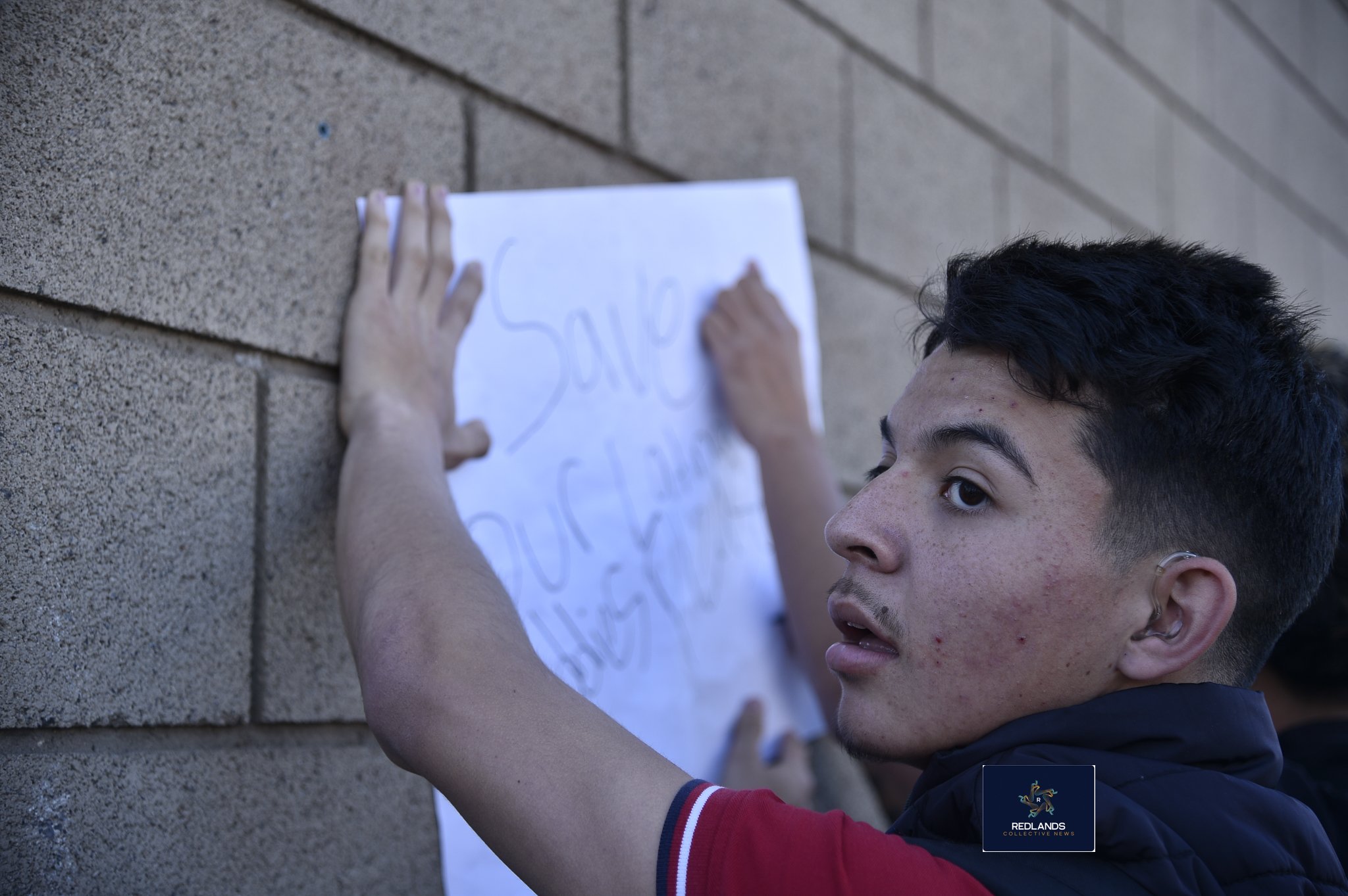  Sebastian Corilliz makes a sign aginst ICE Feb. 13, 2026 in downtown Redlands (Photo by Brian Spears, Redlands News Collective)  