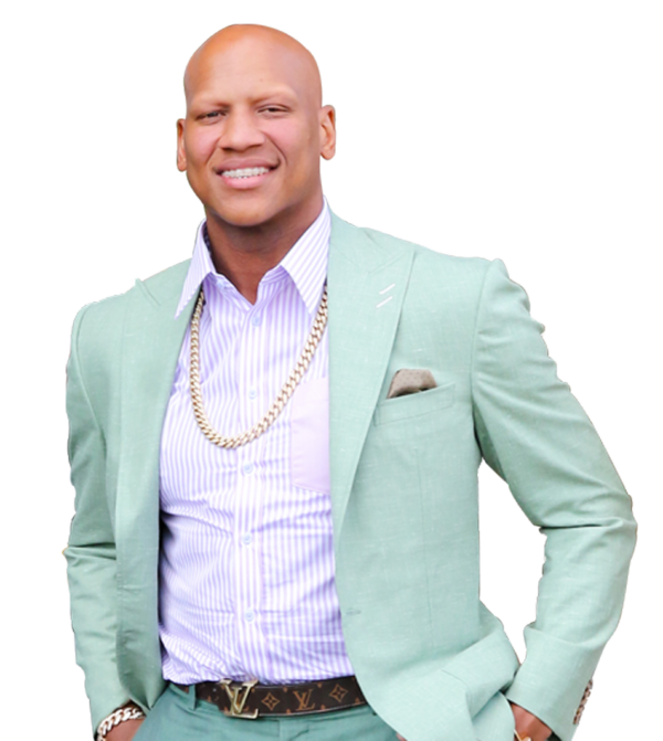 Man in a light mint green suit with a lilac striped shirt, gold chain, and belt, smiling.