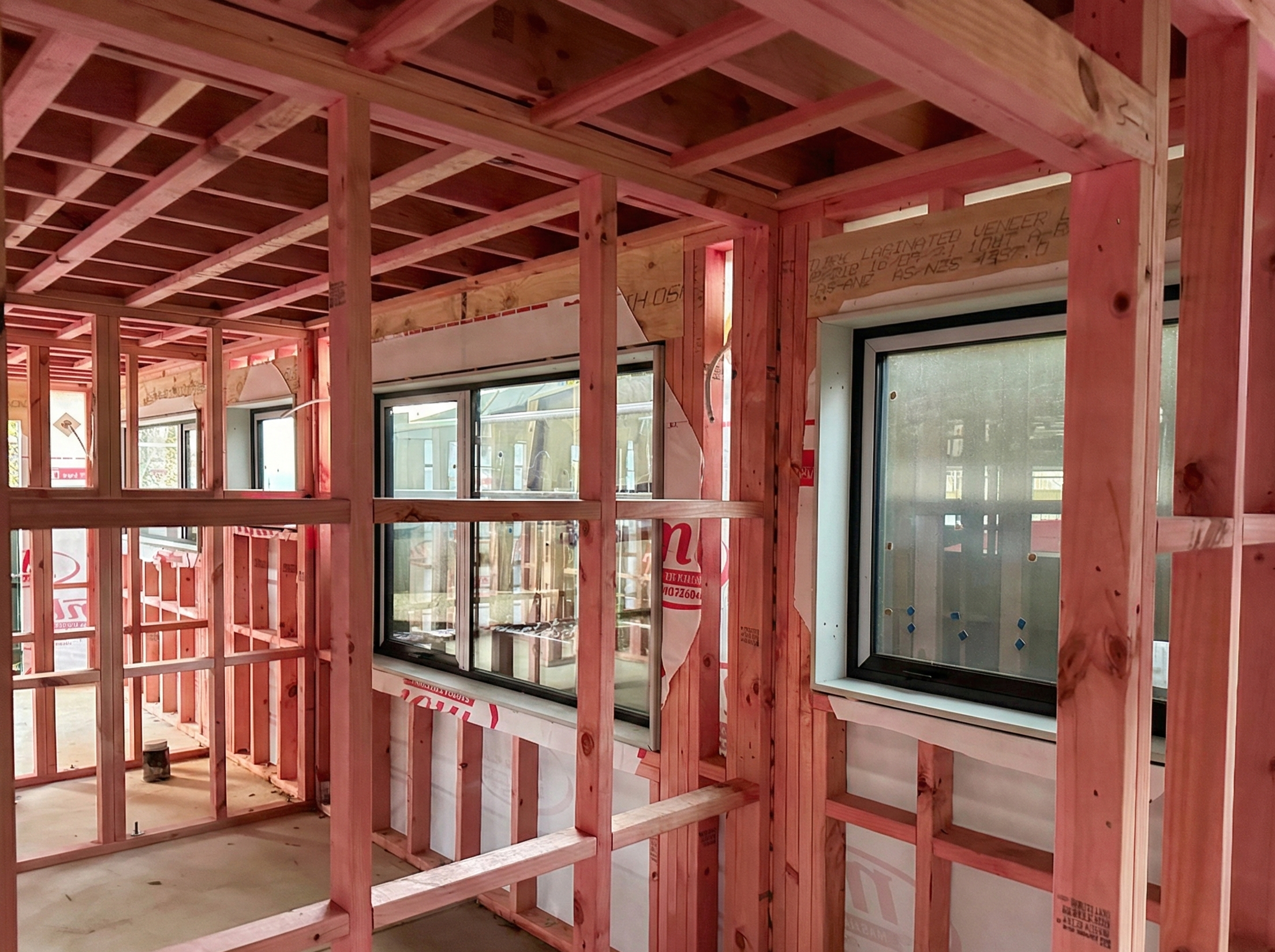 Interior of a house under construction showing wooden framing, windows, and partial walls.