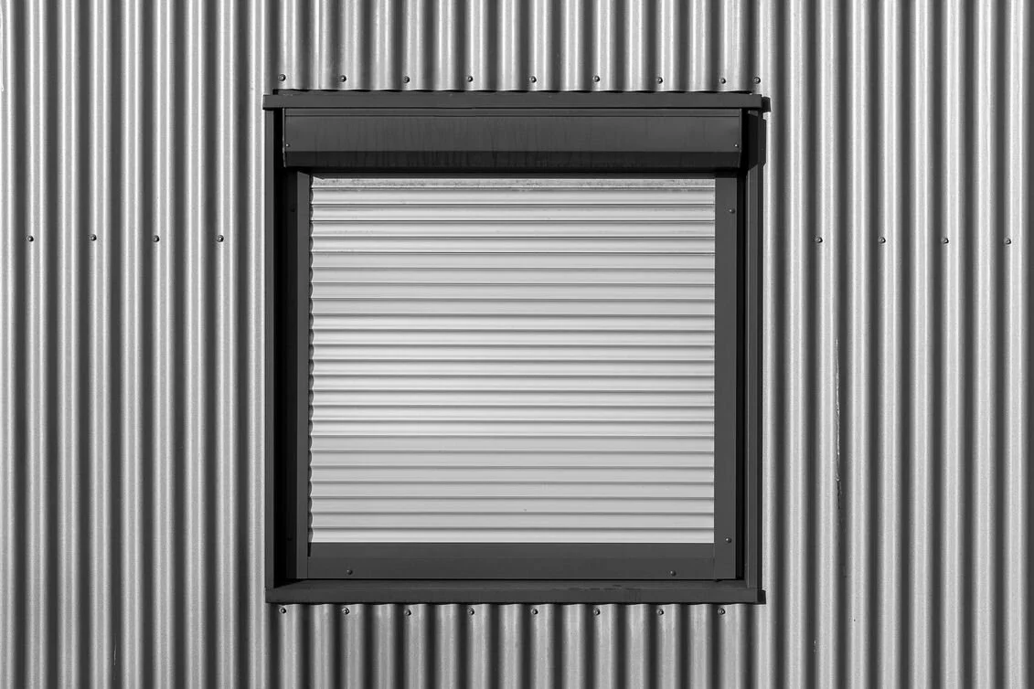 Modern exterior window fully covered by a horizontal aluminum shutter.