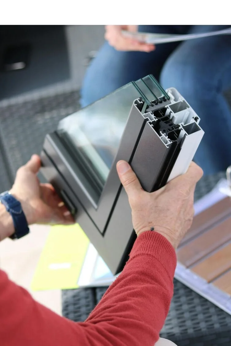 A person showing a cross-section of a window frame with glass and hardware components.