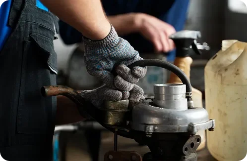 A person wearing gloves working with a metal grinding or cutting tool in a workshop.