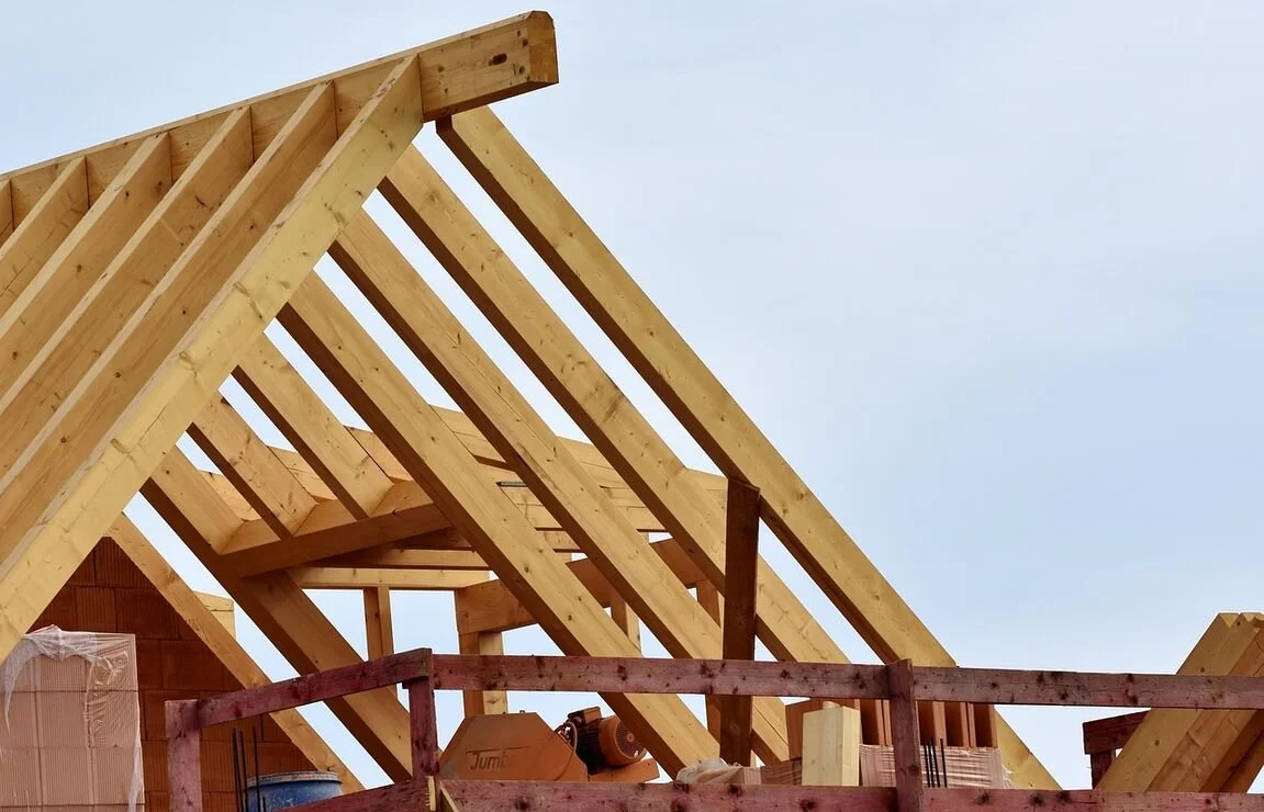 Wooden frame structure of a house under construction against a clear sky.