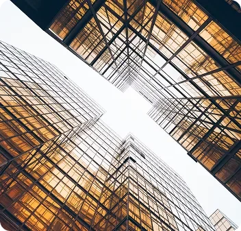Looking up at modern office buildings with glass facades, viewed from the ground.
