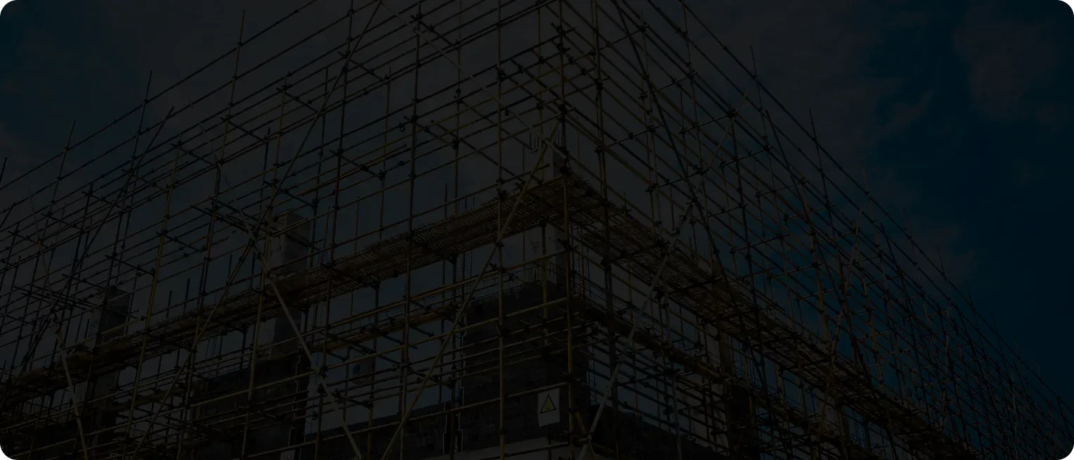 Construction scaffolding surrounding a building under construction against a cloudy sky.