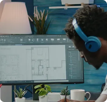 Person wearing blue headphones working on a computer with architectural design software, with houseplants and a lamp in the background.