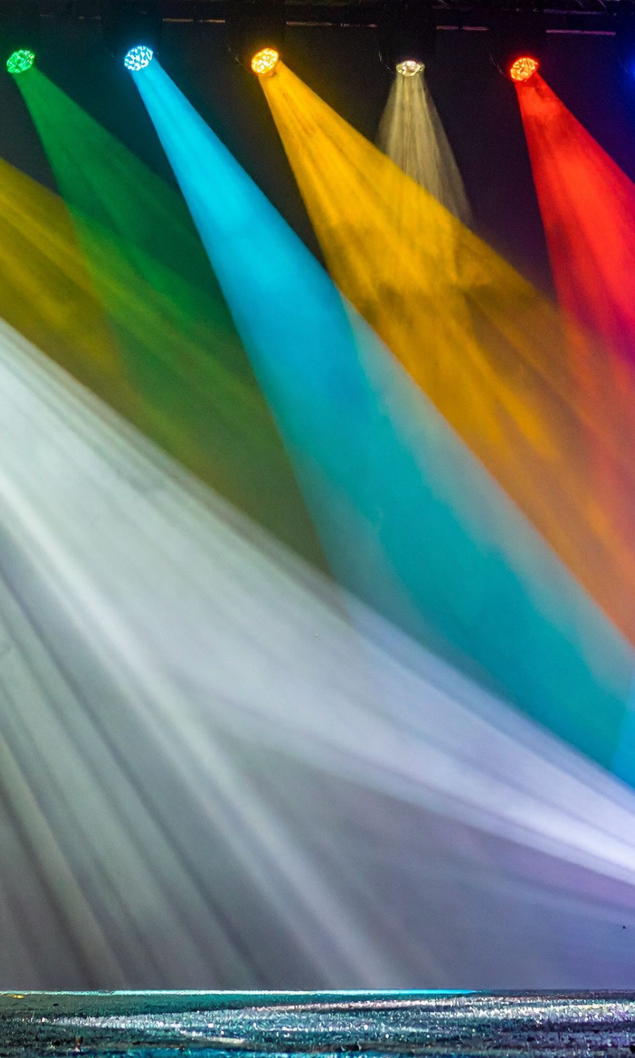 Colorful stage lights shining in green, blue, yellow, white, and red, creating vibrant beams of light.