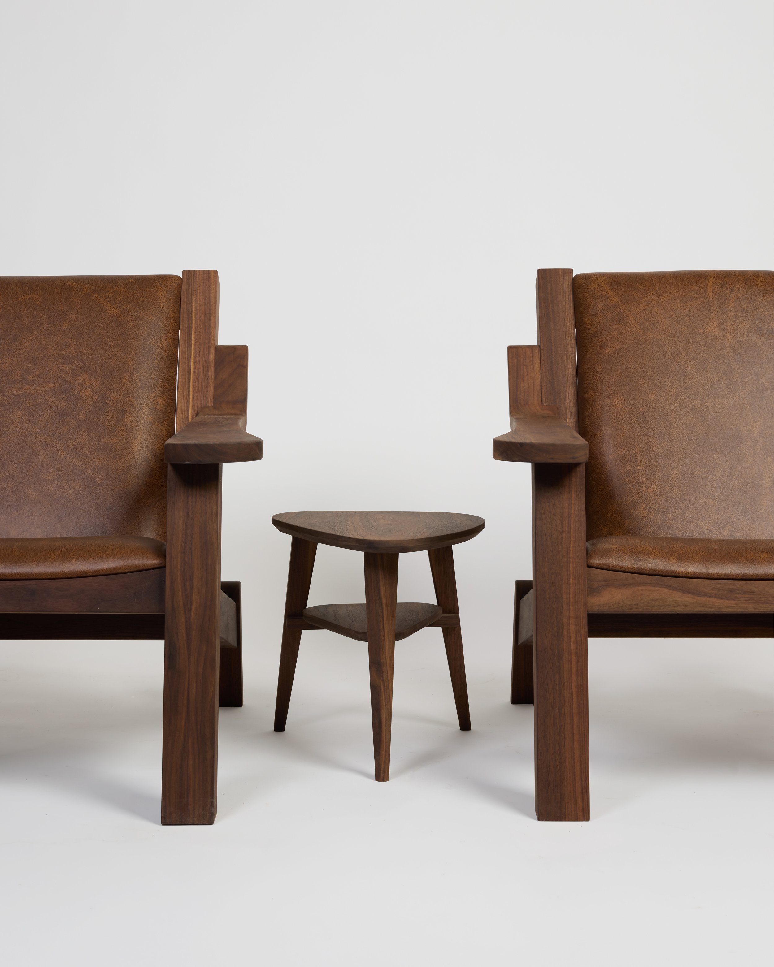 Kin Side Table next to two Walnut Lounge Chairs with leather seats