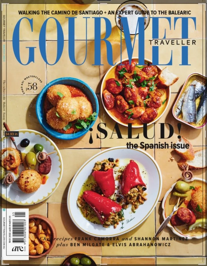 Cover of Gourmet Traveller magazine featuring Spanish cuisine with various tapas dishes, including stuffed peppers, olives, anchovies, and croquettes on a tiled table.