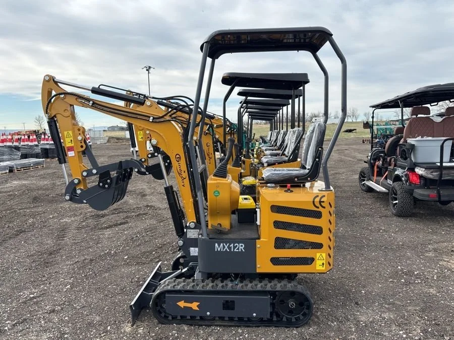 Row of yellow mini excavators with black tracks parked on dirt lot