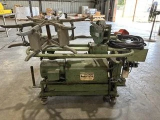 A green woodworking or metalworking machine with various attachments, situated in an industrial or workshop setting.