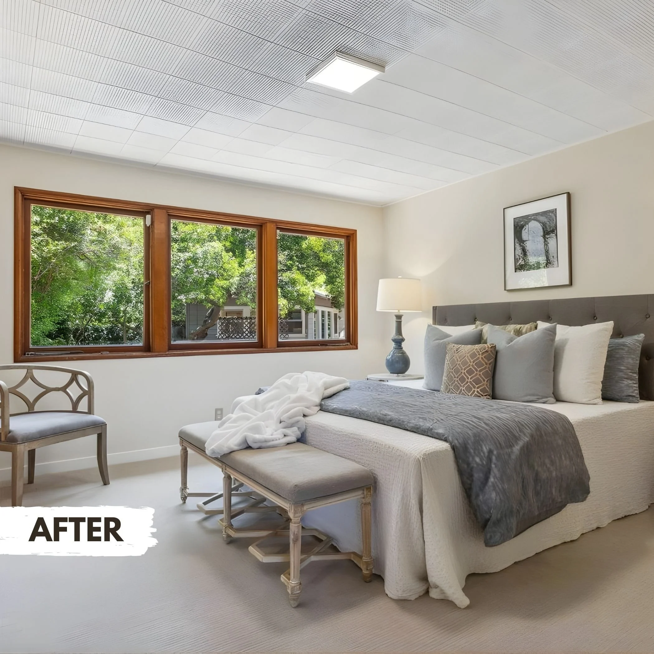 Clean and decorated bedroom with a bed featuring multiple pillows, a nightstand with a lamp, a window with green trees outside, and a white textured ceiling.