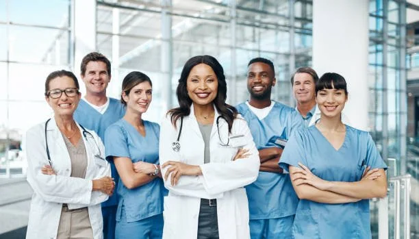 Group of diverse healthcare professionals, including doctors and nurses, standing together in a modern medical facility.
