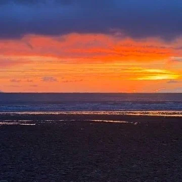 Sunset over the ocean with colorful sky and reflections on the water.