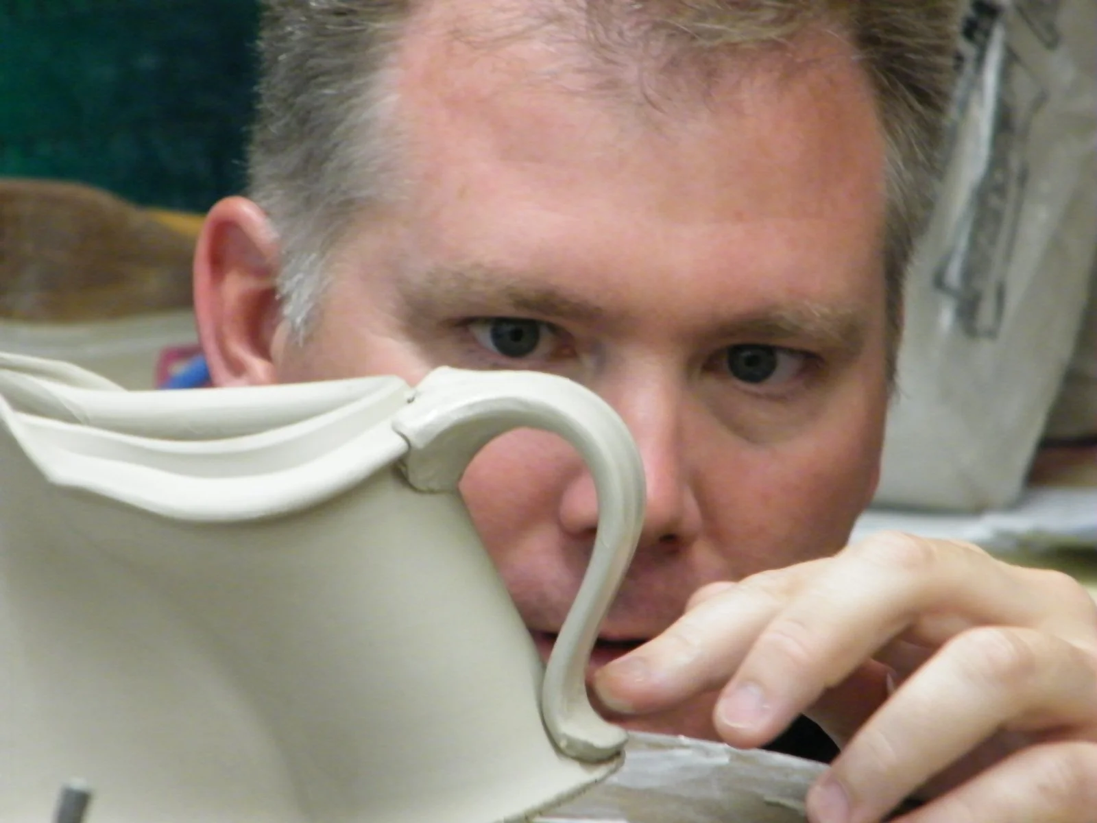 Conner Burns focusing on the details of a ceramic creamer .