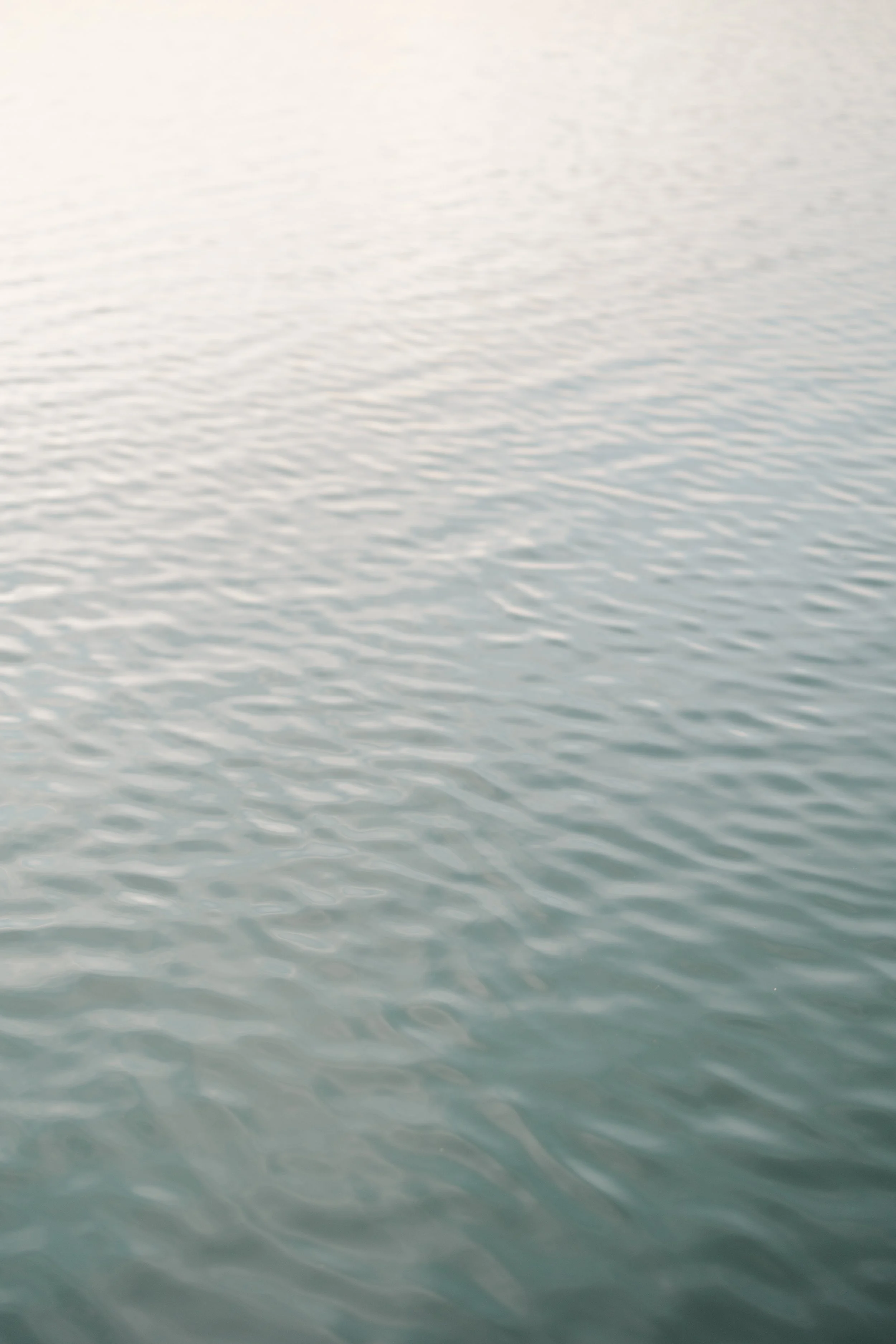 Calm ocean water with gentle ripples under bright light.