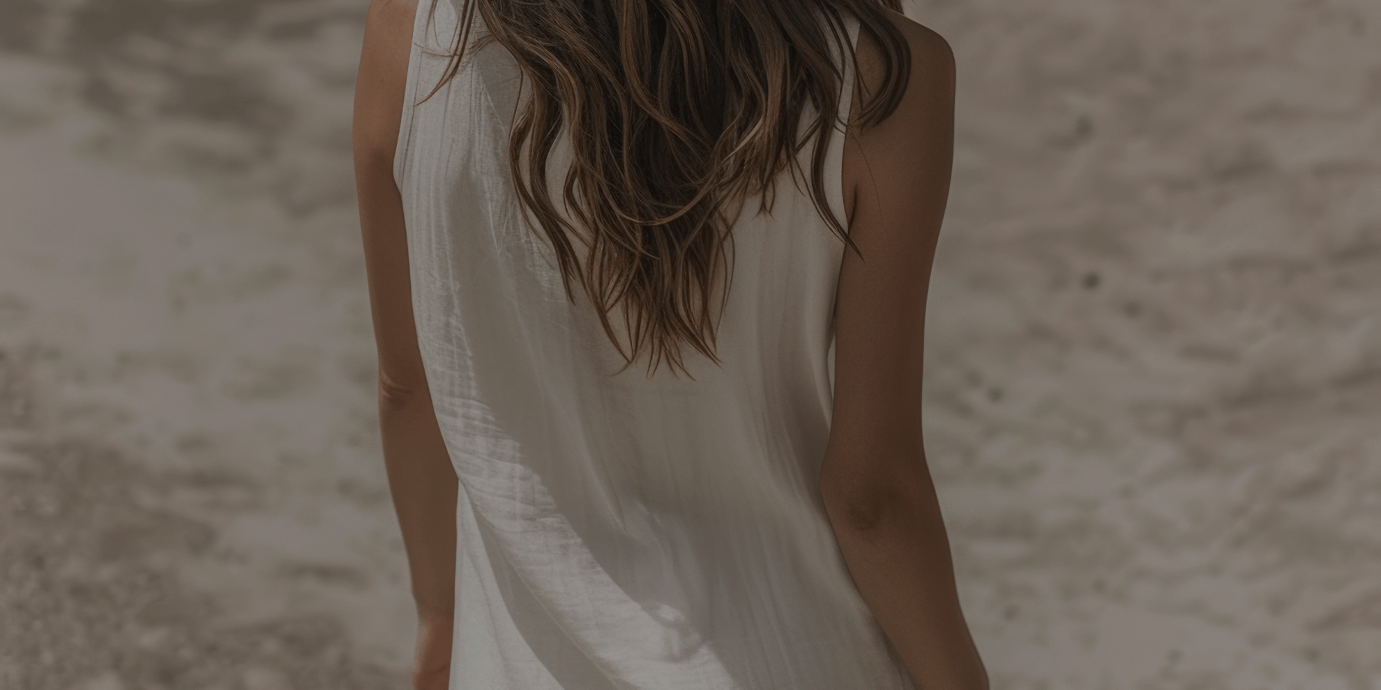 Woman walking down a beach with brown hair