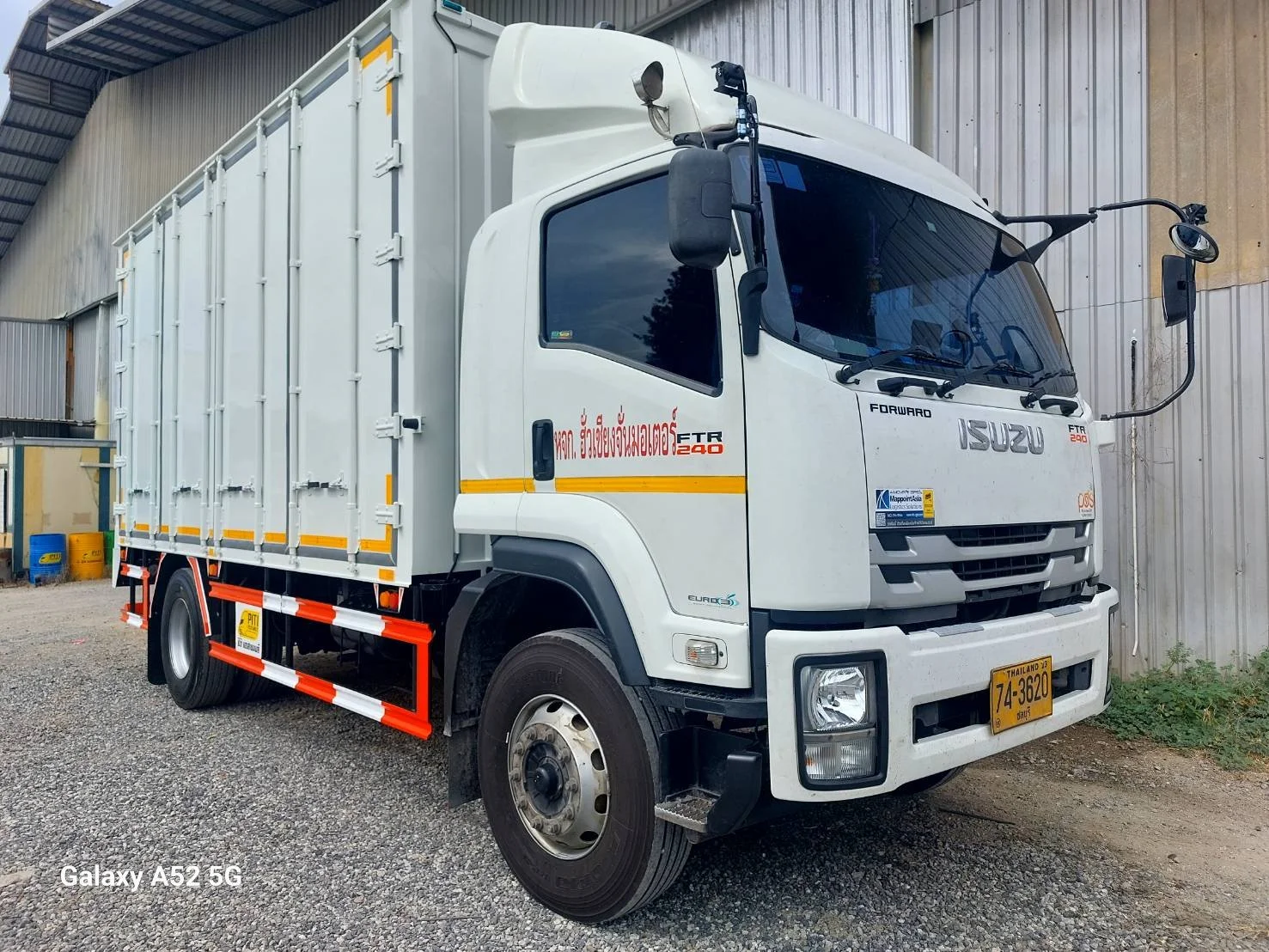 White Isuzu FTR 240 box truck parked beside a building on gravel ground.