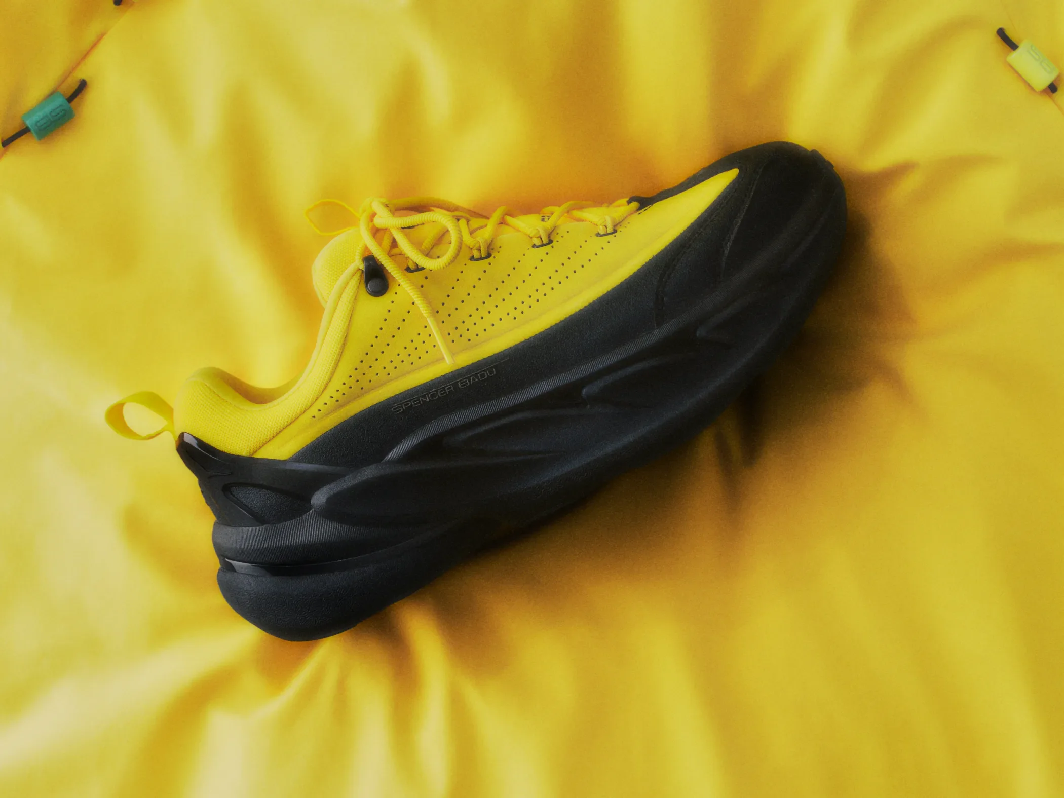 A yellow and black Hoka shoe sits on a yellow backdrop.