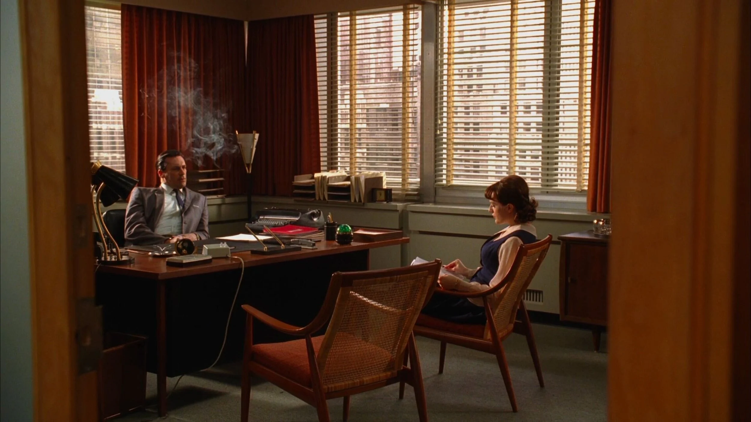 Donald Draper and Peggy Olsen sit at a desk in "Mad Men" scene.