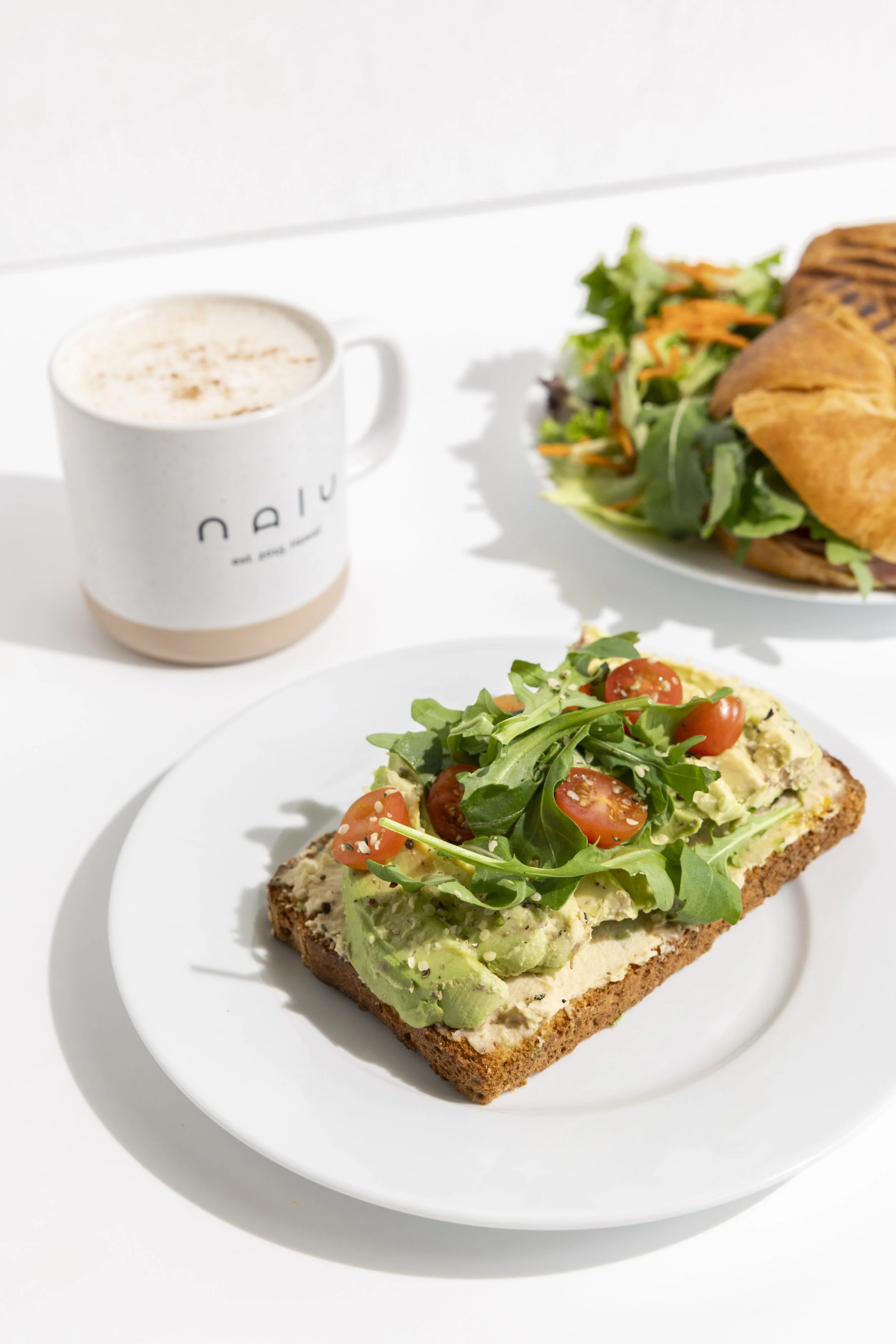 Sliced avocado and cherry tomatoes on toast garnished with arugula and sprinkled with salt and pepper.