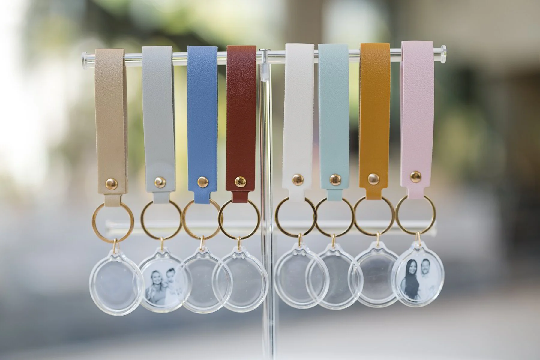 Colorful leather keychains with photo tags hanging on a silver stand.