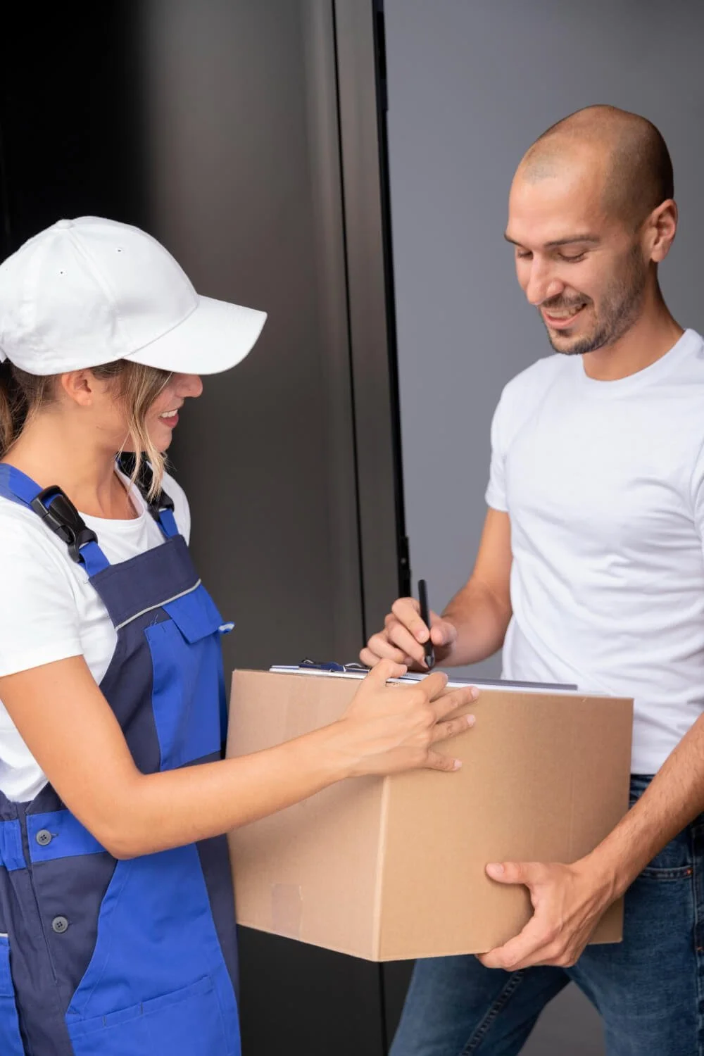 A woman in a white shirt, blue overalls, and white cap handing a package to a man in a white shirt, as part of a delivery or courier service.