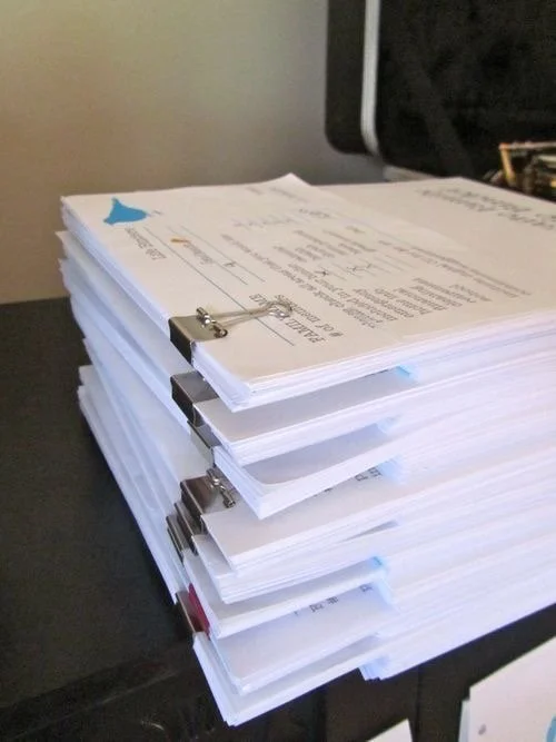 A large stack of printed documents clipped together, placed on a black table.
