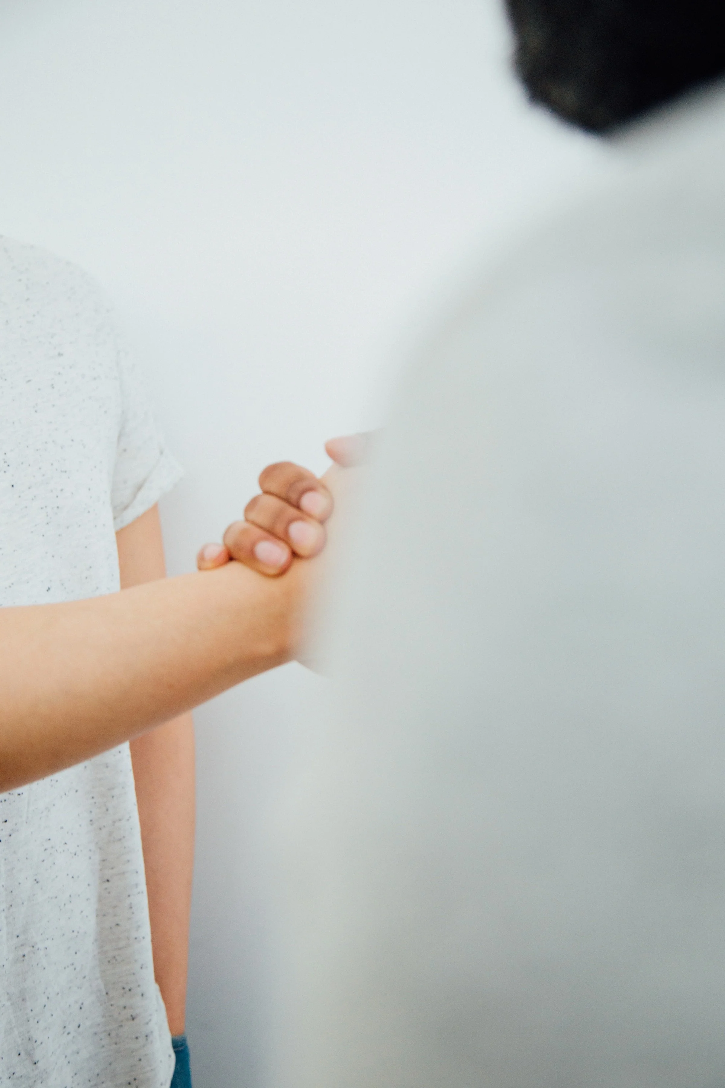 Two individuals shaking hands in a friendly manner against a plain background.