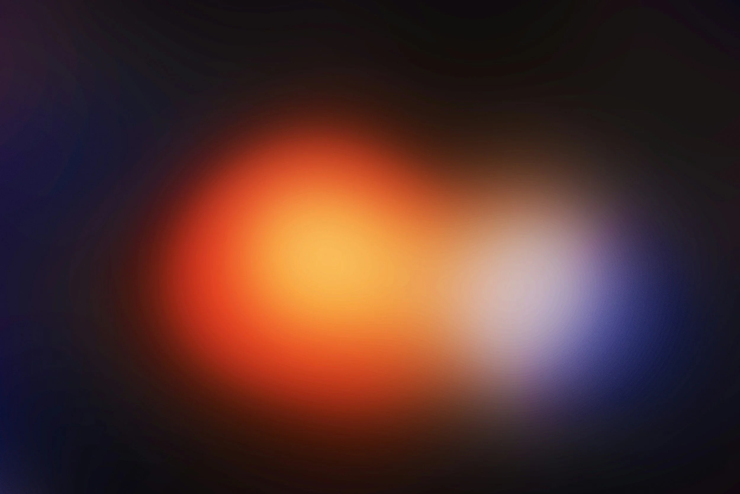 Blurred image with a central orange-red glow, surrounded by darker shades of black, blue, and purple.