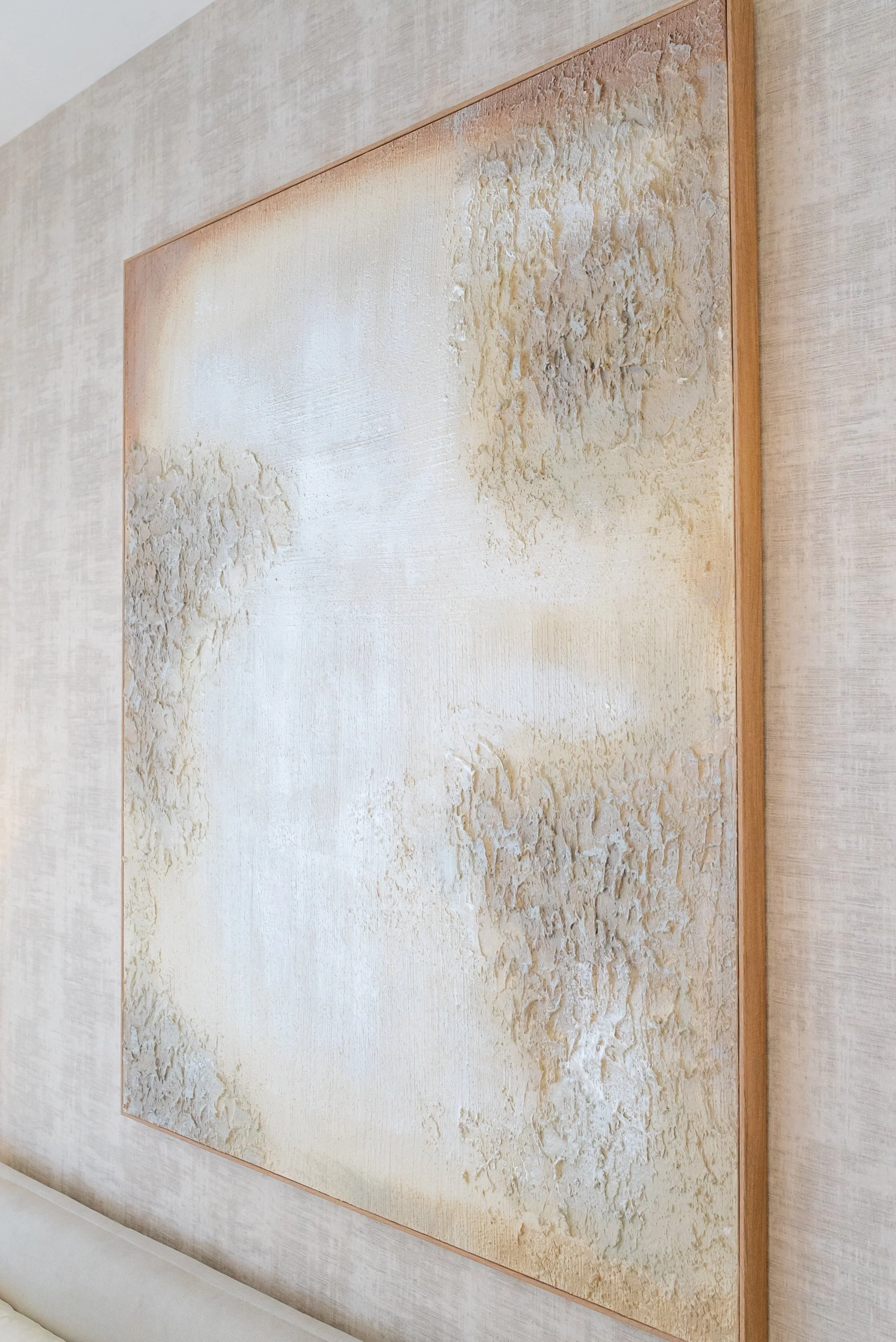 Abstract textured artwork in neutral tones, framed on a wall.