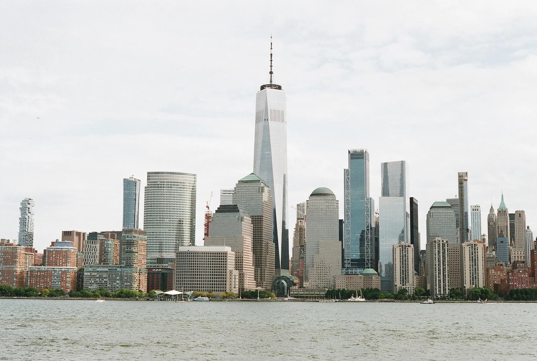 Skyscrapers in New York City viewed from across the water, with One World Trade Center prominently in the center.