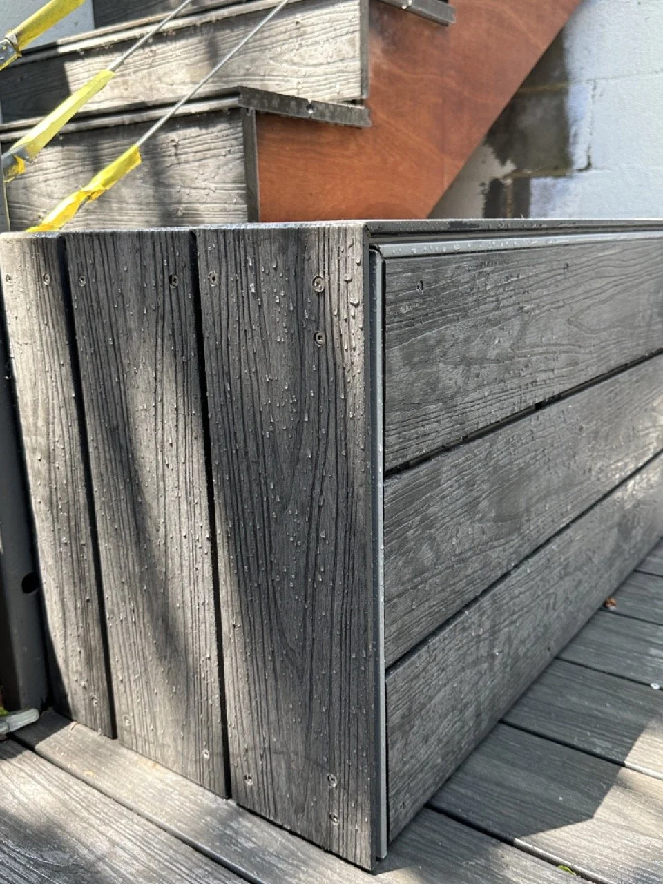 Close-up of weathered gray wooden deck with water droplets on the surface.