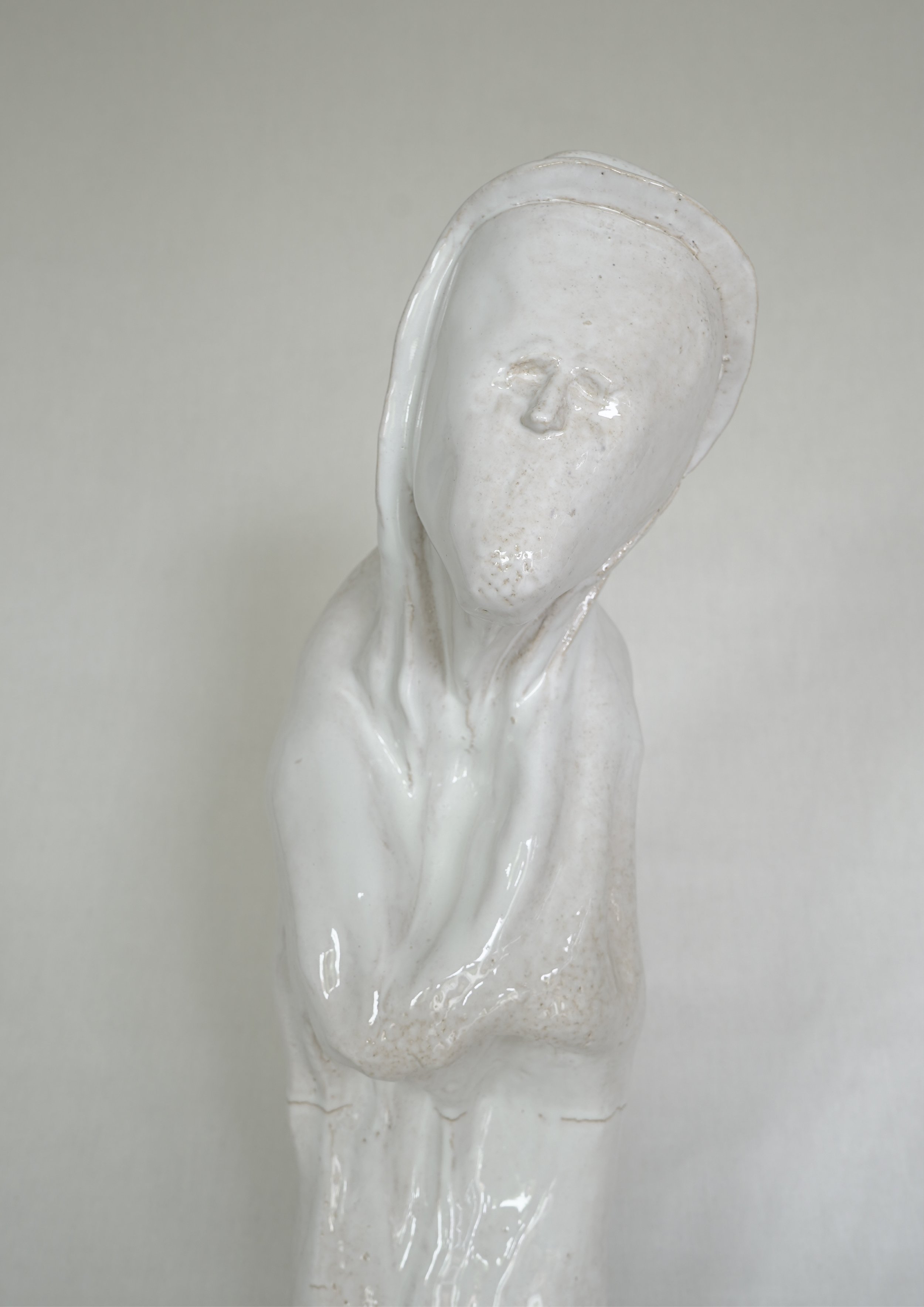 Weiße Keramikfigur einer Person mit langem Hals und geschlossenen Augen, die eine schlichte, elegante Erscheinung hat.