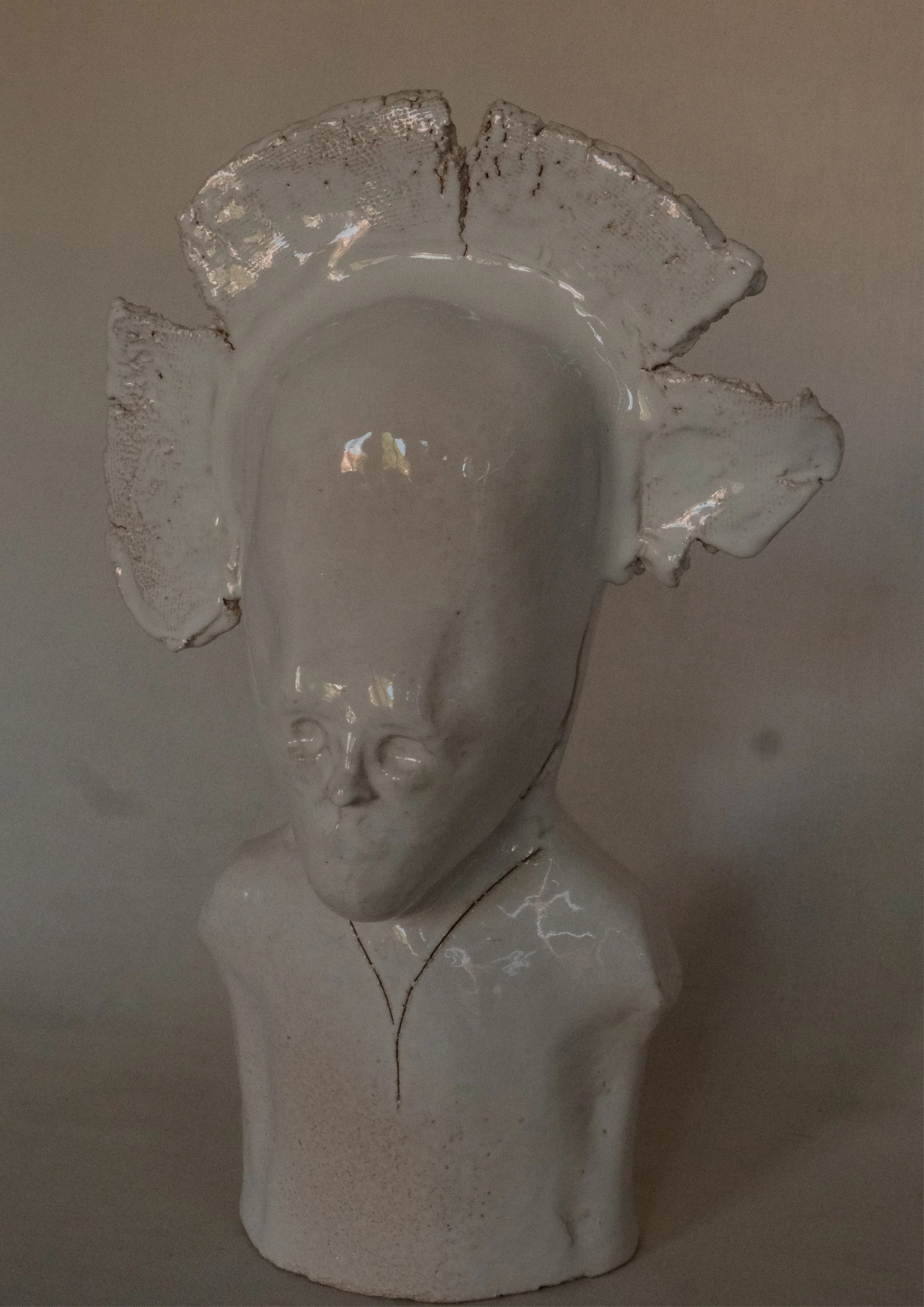 Skulptur einer menschlichen Figur mit einem leeren, glasähnlichen Kopf, an dem ein fragiler, blumenähnlicher Kopfaufsetzer angebracht ist.