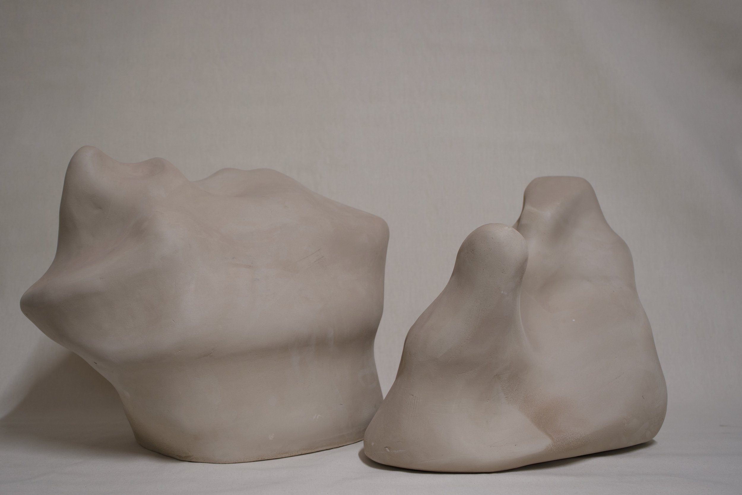 Drei unregelmäßig geformte, helle Skulpturen aus Keramik auf weißem Hintergrund