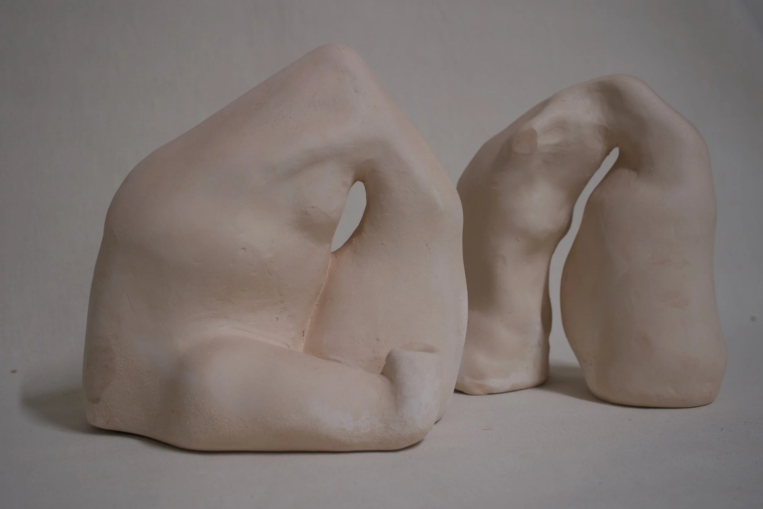 Drei abstrakte, weißliche Skulpturen mit organischen Formen auf neutralem Hintergrund