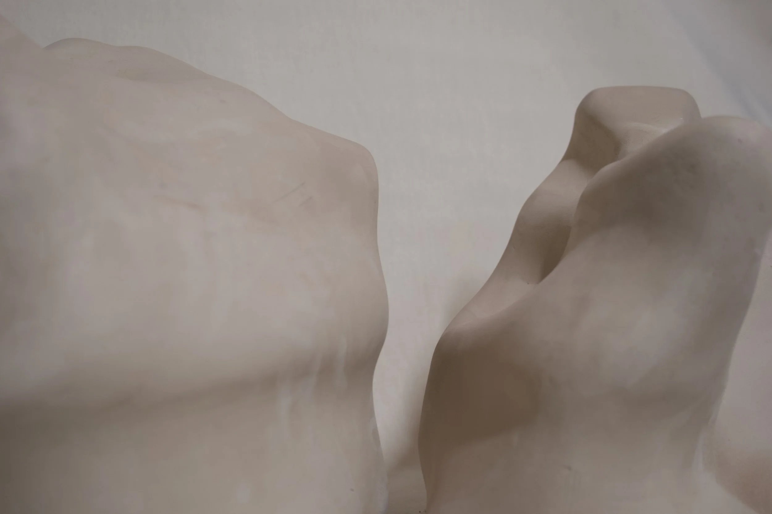 Nahaufnahme von abstrakten Skulpturen aus hellem Material, die kurvige und organische Formen haben.