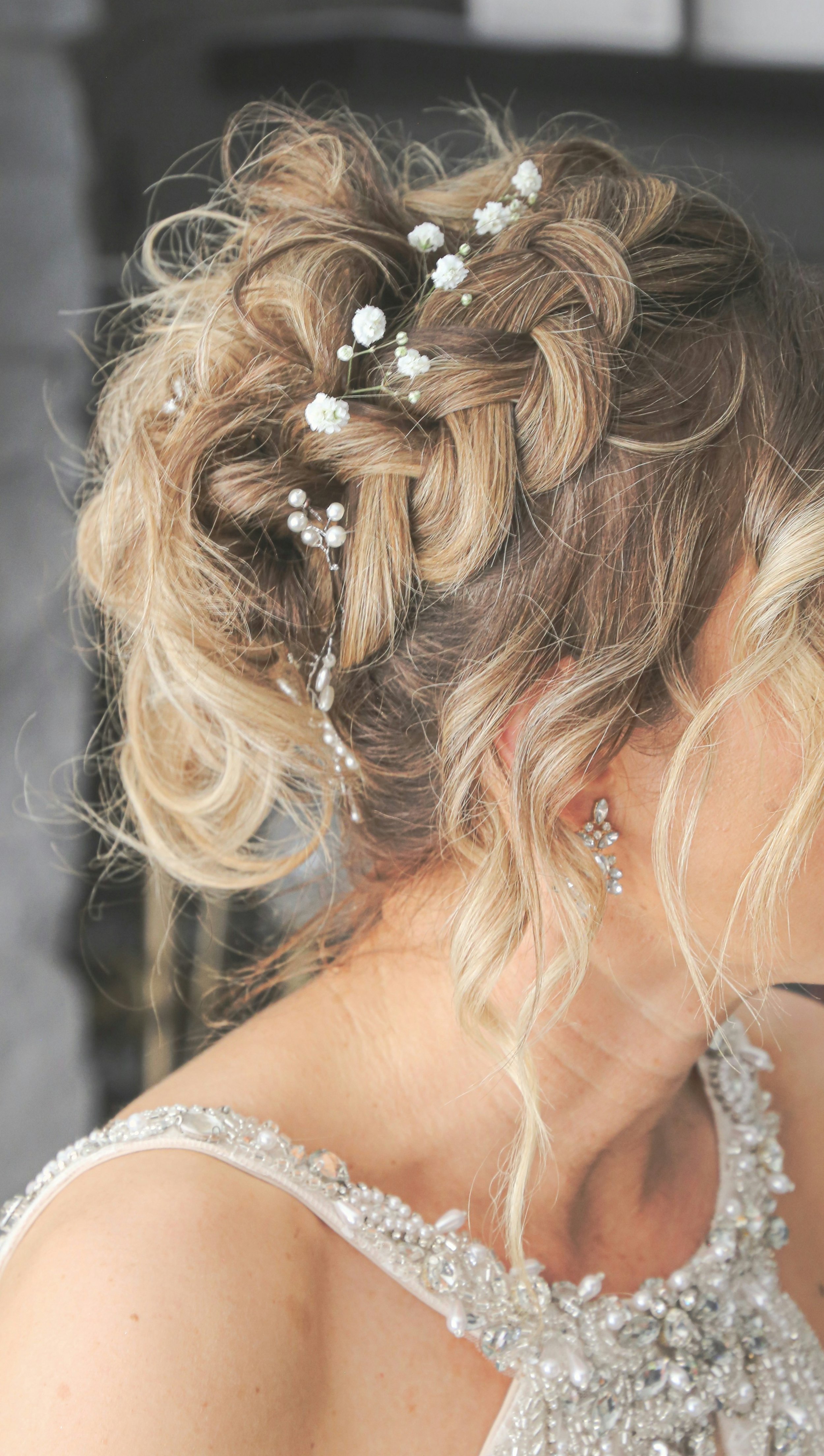 Bridal updo hairstyle with braided details and delicate floral hair pins, styled for a wedding hair trial.