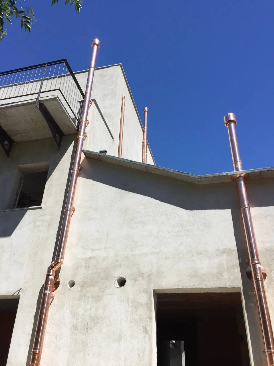 Edificio in costruzione con canaline di rame visibili contro un cielo blu