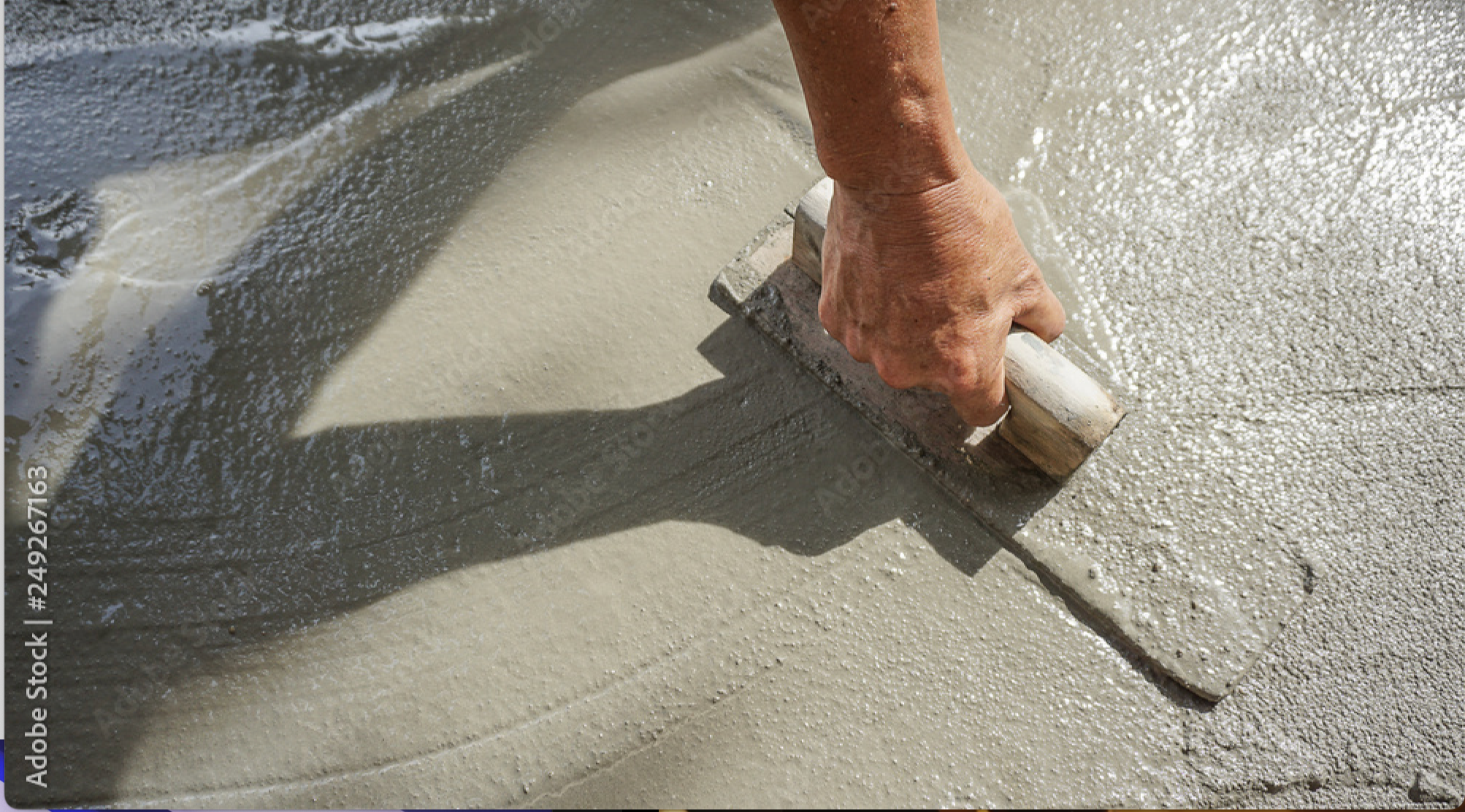 A person using a trowel to smooth wet concrete on a sidewalk or patio.