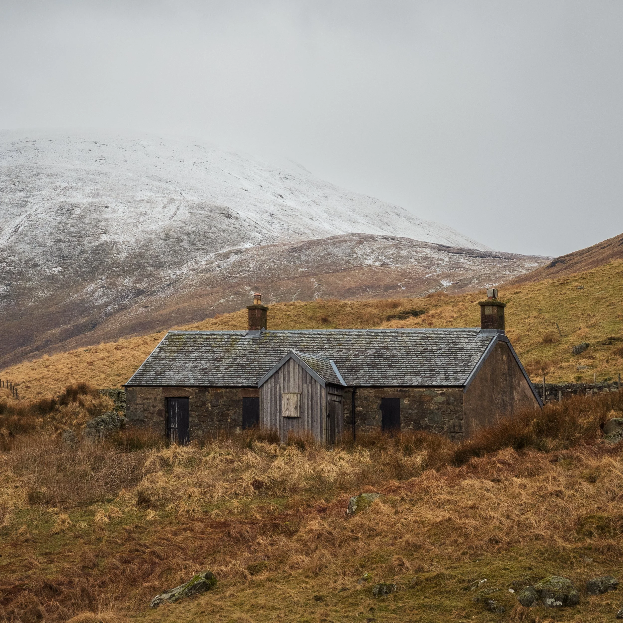 Arivurichardich Bothy with a snow-covered mountain in the background.
