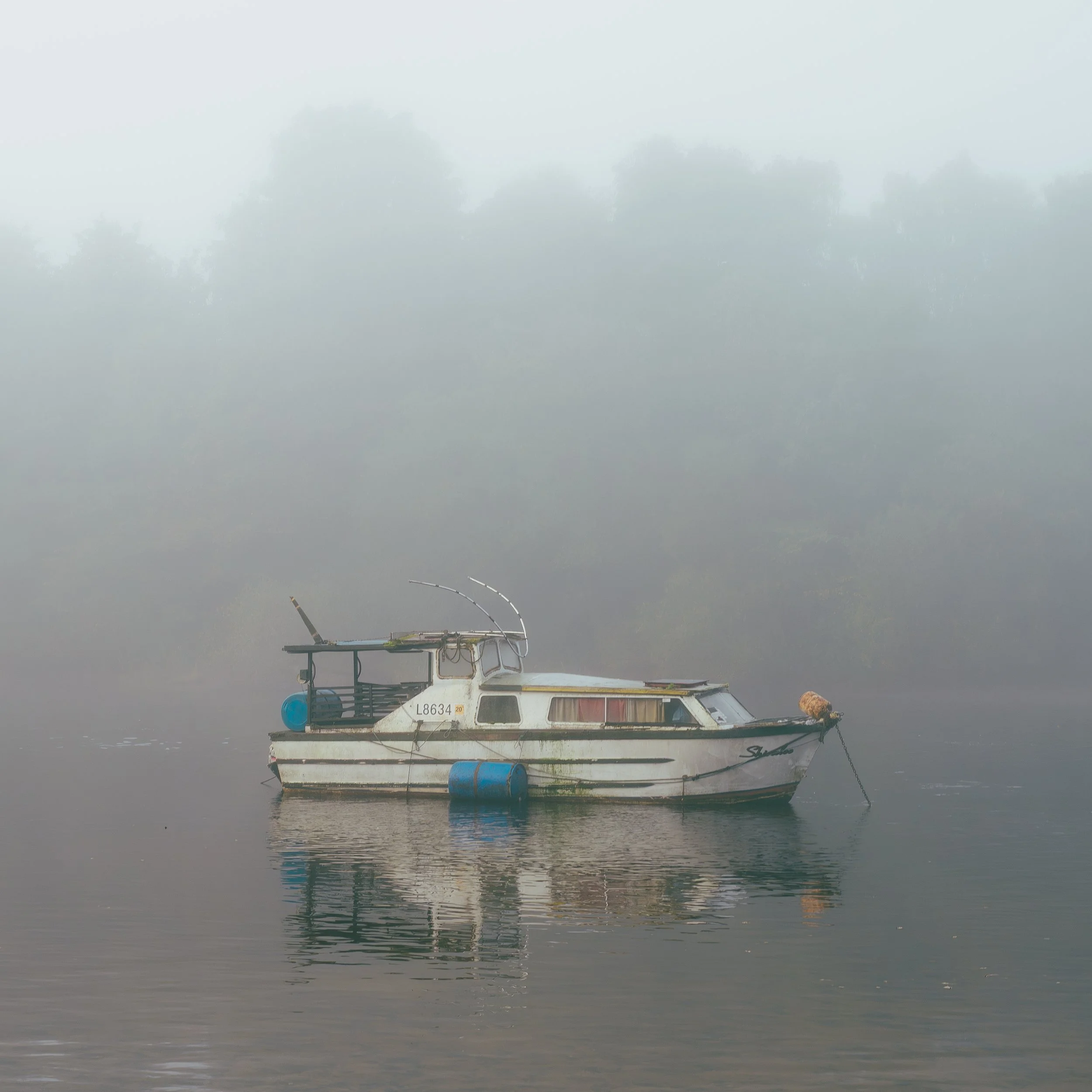 A boat floating on Loch Lomond with fog in the background.
