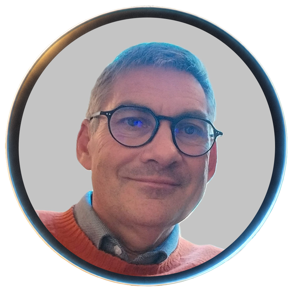 A middle-aged man with gray hair, glasses, and a slight smile, wearing an orange sweater over a collared shirt.