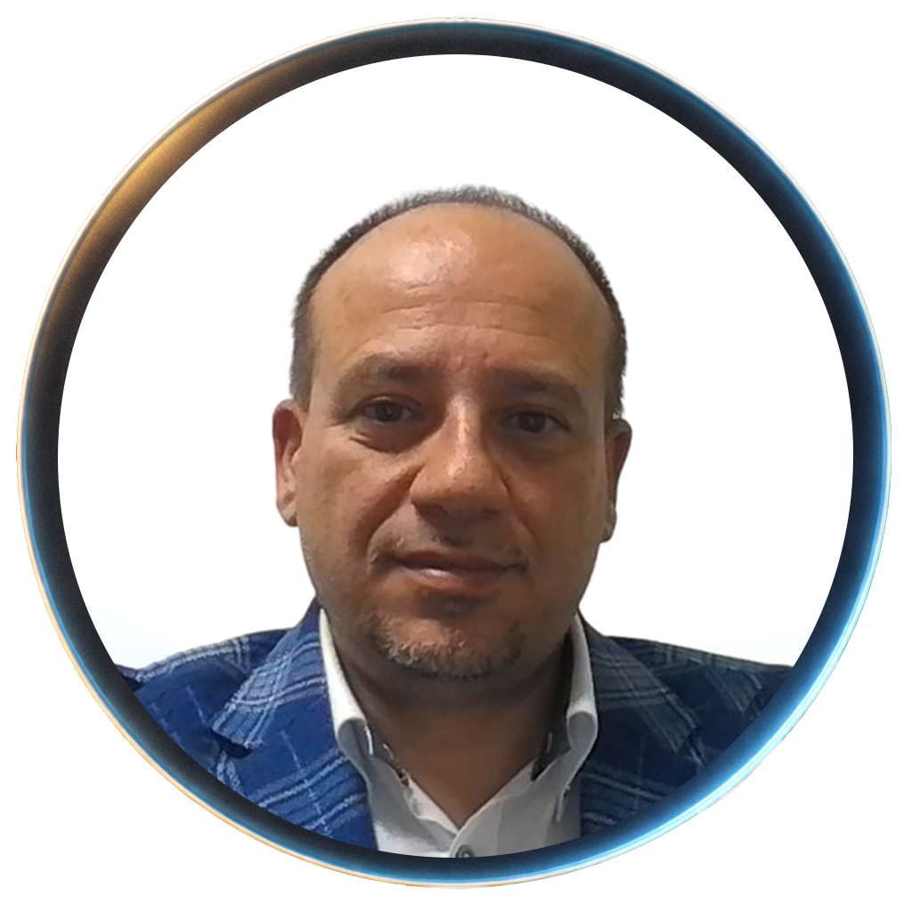 Close-up portrait of a man with short dark hair, lightly tanned skin, wearing a white dress shirt and a blue plaid blazer, against a white background.