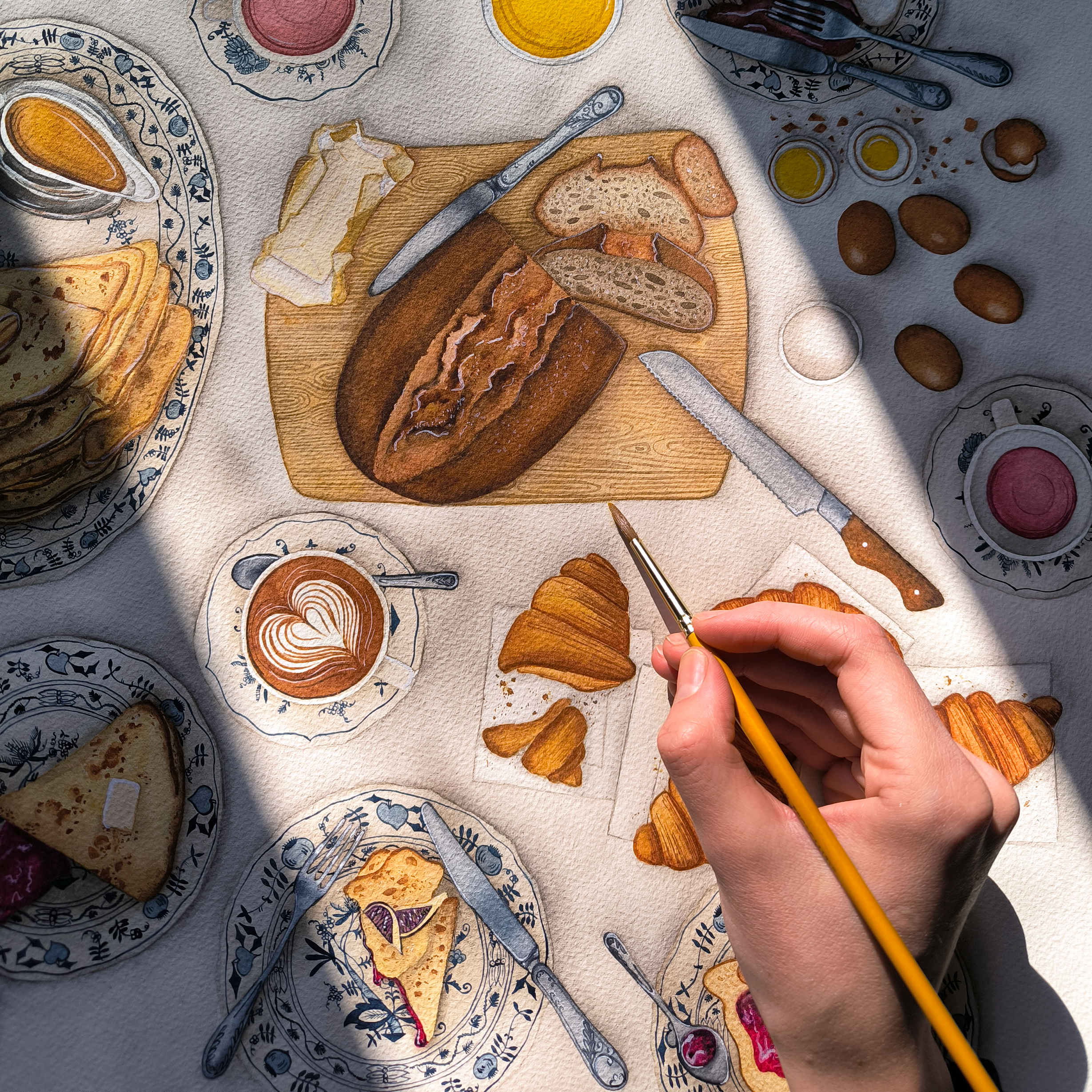 A table set for breakfast with an artist painting a drawing of a breakfast scene, including bread, croissants, coffee, eggs, and fruit, with various plates, cups, and utensils, watercolor illustration