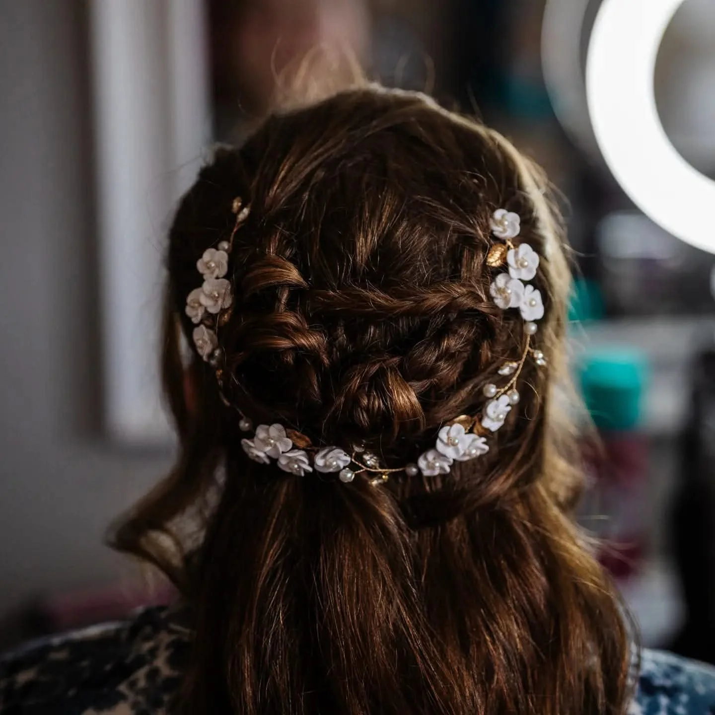 Back of a woman's head with braided hair adorned with a floral hair accessory.