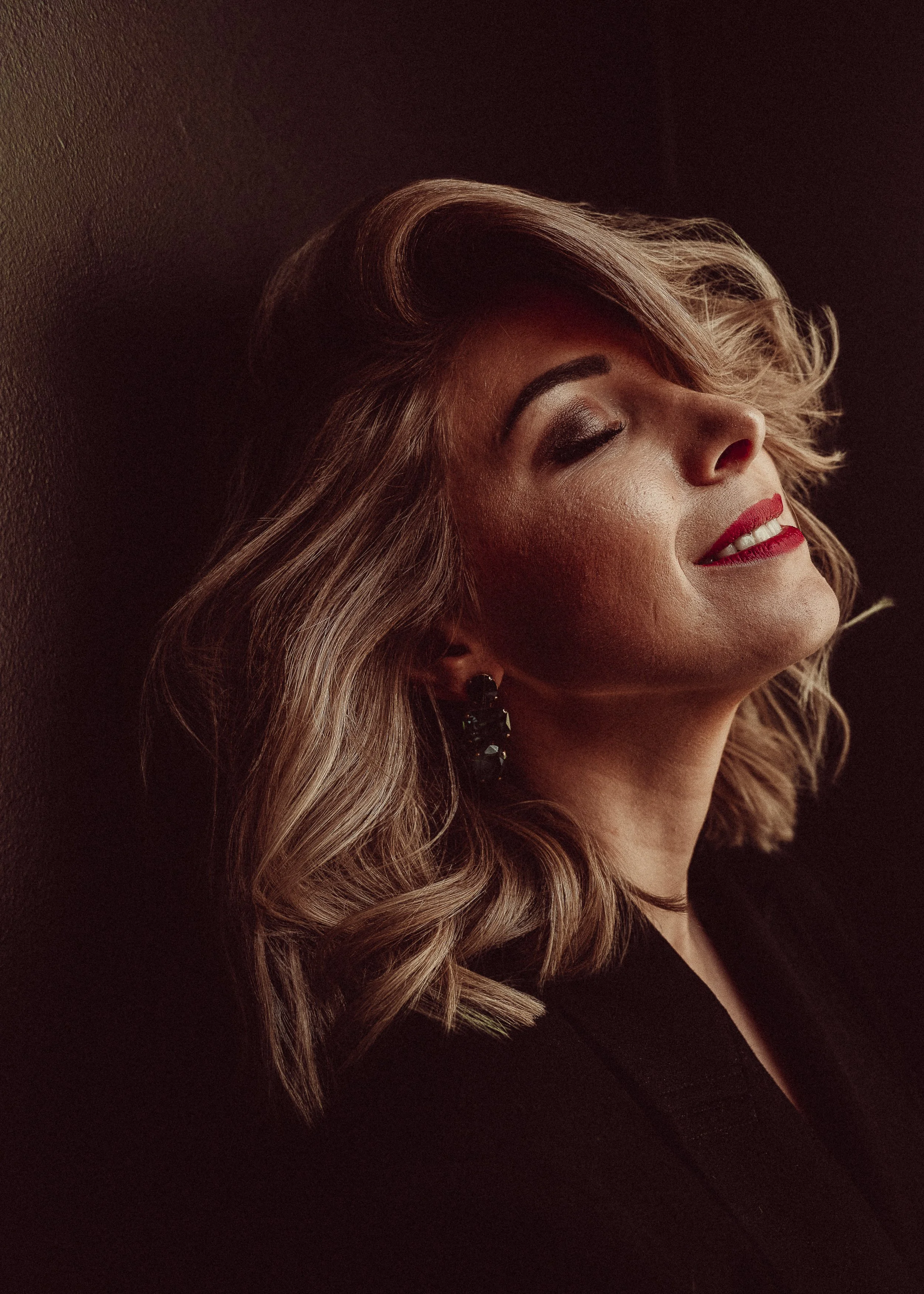 vrouw met blond haar, ogen dicht en rode lipstick.