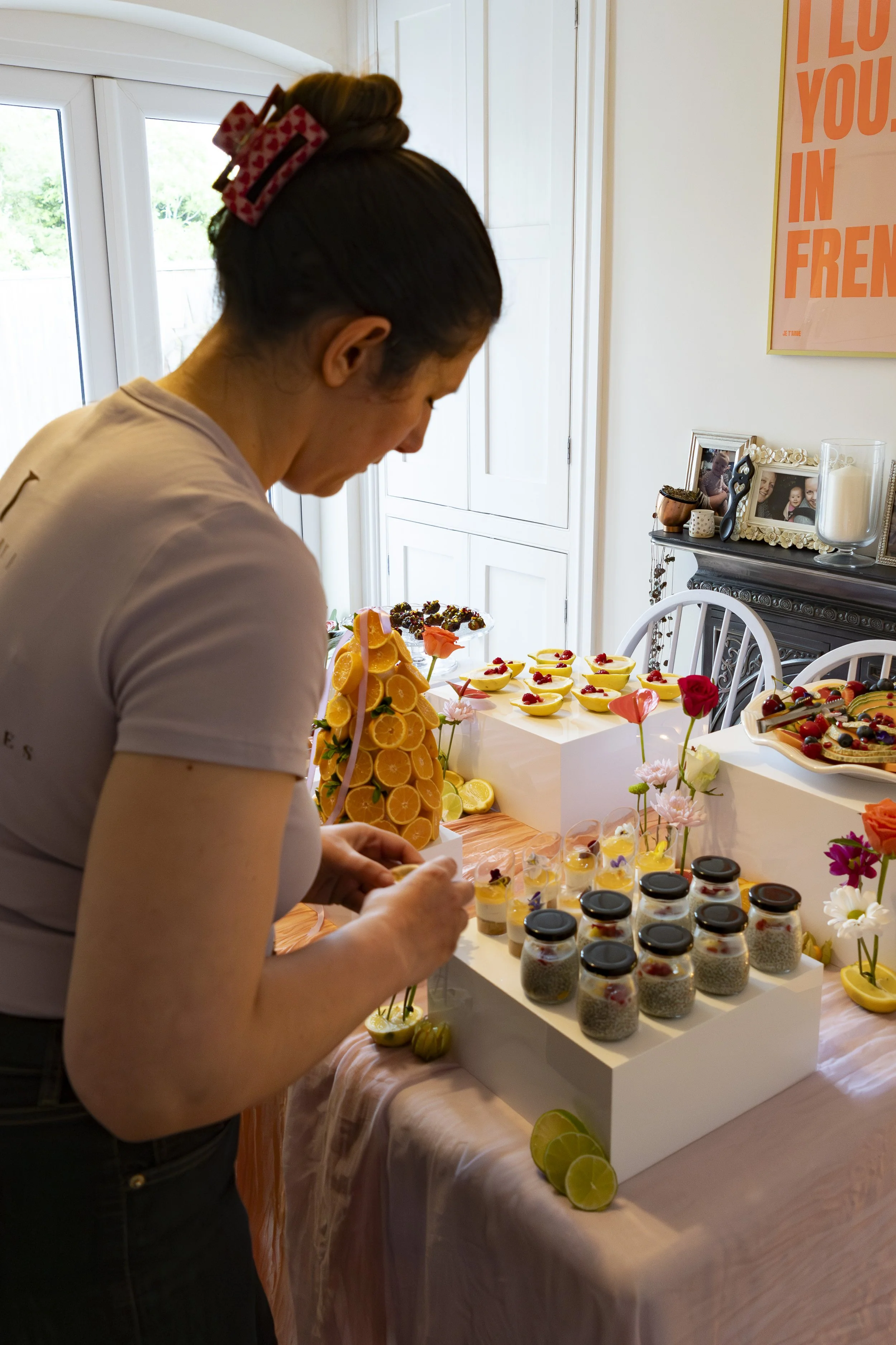 A woman with hair in rollers decorating lemon desserts on a table.
