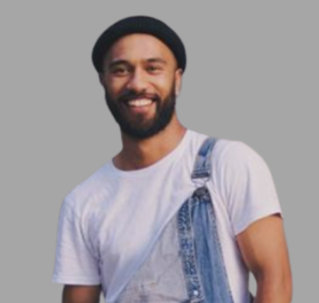 A smiling man with a beard wearing a black hat, a white t-shirt, and denim overalls against a gray background.